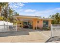 Cozy single-story home with front yard and carport, surrounded by tropical landscaping, and a white picket fence at 5807 De Palmas Ave, Holmes Beach, FL 34217