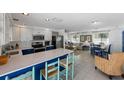 Open concept kitchen with modern white cabinets, stainless steel appliances, blue island and adjacent dining area at 5807 De Palmas Ave, Holmes Beach, FL 34217