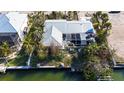 Aerial view showcases the property's screen lanai, metal roof, and lush waterfront location at 607 Baronet Ln, Holmes Beach, FL 34217