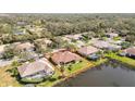 Aerial view of a home with a red-tiled roof, showcasing its proximity to a peaceful lake and manicured landscaping at 6637 Deering Cir, Sarasota, FL 34240