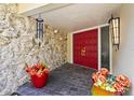 Inviting front porch with double red doors, stone accents, and colorful potted plants at 6640 Peacock Rd, Sarasota, FL 34242