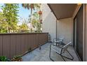 View of the exterior balcony featuring chairs, a small table, and a wooded view at 1680 Brookhouse Cir # 110, Sarasota, FL 34231