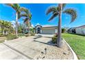 Inviting home with an extended driveway flanked by lush landscaping and towering palm trees at 221 Fairway Rd, Rotonda West, FL 33947