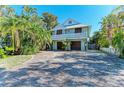 Inviting two-story home features lush landscaping, a welcoming front porch, and a spacious driveway at 2308 Canasta Dr, Bradenton Beach, FL 34217