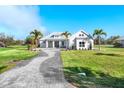 Beautifully landscaped single-story home with a long brick driveway and bright blue sky at 28960 Gin Ln, Punta Gorda, FL 33982