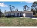 Single-story home boasts a neutral exterior, attached two-car garage, and a neatly landscaped front yard at 2877 Sultan Ct, North Port, FL 34286