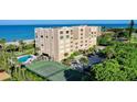 Beautiful aerial view of condo building with tennis court, lush landscaping, and private beach access at 2675 Gulf Of Mexico Dr # 301, Longboat Key, FL 34228