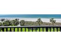 Beautiful beach view with palm trees and white sand, seen from a balcony with black railings at 2675 Gulf Of Mexico Dr # 301, Longboat Key, FL 34228