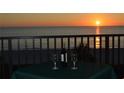 Balcony table set with wine and glasses overlooks a stunning beach sunset at 2675 Gulf Of Mexico Dr # 301, Longboat Key, FL 34228