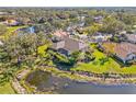 A home with a screened-in pool is surrounded by lush greenery and a tranquil pond in this aerial view at 4477 White Cedar Trl, Sarasota, FL 34238
