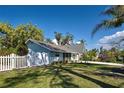 Charming single-story home featuring a well-manicured lawn, white picket fence, and mature trees at 470 Leach St, Englewood, FL 34223