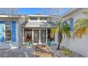 Close up of home entrance with tiled walkway, decorative doors, and blue shutters at 710 Birdsong Ln, Sarasota, FL 34242