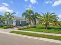 Charming home with a manicured lawn, lush tropical landscaping, and a brick paver driveway at 8271 Redonda Loop, Bradenton, FL 34202