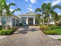 Lovely home with a brick driveway, two-car garage, a well-manicured lawn, and vibrant landscaping at 8271 Redonda Loop, Lakewood Ranch, FL 34202