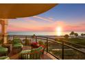 Relaxing balcony with beautiful ocean views, comfortable seating, and vibrant red flowers at sunset at 2141 Gulf Of Mexico Dr Unit # 4, Longboat Key, FL 34228