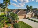 Aerial view of a well-maintained single-story home with tile roof, lush landscaping, and a spacious driveway at 375 Fairway Isles Ln, Bradenton, FL 34212