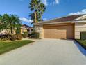 Beautiful home featuring well-maintained landscaping, mature palm trees, and a spacious two-car garage at 375 Fairway Isles Ln, Bradenton, FL 34212