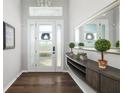 Bright entryway featuring a modern front door, elegant mirror, stylish console table, and gleaming hardwood floors at 438 Whistler Gln, Bradenton, FL 34212
