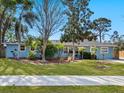 Charming home showcasing lush landscaping, mature trees, and manicured lawn enhancing curb appeal at 2376 Novus St, Sarasota, FL 34237
