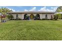 Inviting home exterior with a lush lawn, arched entryway, and cheerful yellow door at 641 Verrocchio Dr, Nokomis, FL 34275