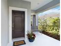 Cozy, covered front porch featuring seating and a decorative potted plant near a stylish, modern door at 11231 Woodlake Way, Parrish, FL 34219