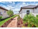 Side view of a single Gathering home with a paver walkway and lush landscaping leading to the backyard at 16119 Fortezza Dr, Bradenton, FL 34211