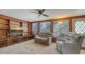 Cozy living room featuring wood paneling, a ceiling fan, and comfortable seating near bright windows at 3365 7Th St, Sarasota, FL 34237