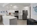 Modern kitchen features white cabinets, stainless appliances, quartz counters, and mosaic tile backsplash at 5279 Isla Key S Blvd # 113, St Petersburg, FL 33715