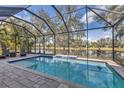 A beautiful screened-in pool with brick pavers overlooks a serene lake and lush landscaping at 12046 Forest Park Cir, Bradenton, FL 34211