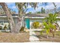 Inviting home exterior featuring a turquoise door and lush landscaping at 1409 2Nd E Ave, Bradenton, FL 34208