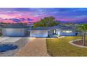 Charming single-story home boasting a paver driveway, separate garage, and freshly landscaped yard at dusk at 1950 Fairview Dr, Englewood, FL 34223