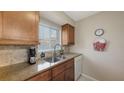 Kitchen with stainless steel sink, faucet, granite countertops, tile backsplash, and wood cabinets at 2620 Hidden Lake N Dr # B, Sarasota, FL 34237
