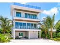 Beautiful three-story home with balconies and tropical landscaping at 870 N Shore Dr, Anna Maria, FL 34216