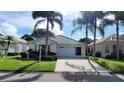 Charming single-story home features a well-manicured lawn, mature palm trees, and an attached two-car garage at 26311 Seminole Lakes Blvd, Punta Gorda, FL 33955