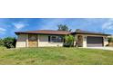 Single-story home with a brown roof, attached garage, and lush lawn at 745 Columbia St, Port Charlotte, FL 33948