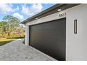 Close-up of the sleek dark garage door featuring modern lighting fixtures at 5823 Kumquat Ave, North Port, FL 34291