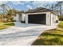 Modern home showcasing a dark garage door and stone-paved driveway at 5823 Kumquat Ave, North Port, FL 34291