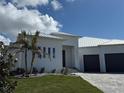 An elegant front exterior with a paved driveway, metal roof, black front doors and a three-car garage at 1426 Mineo Dr, Punta Gorda, FL 33950