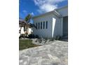 A modern white house with a metal roof, minimalist landscaping, and a paved driveway with stone pavers at 1426 Mineo Dr, Punta Gorda, FL 33950
