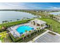 Community pool with a clubhouse, surrounded by lush landscaping and a lake at 42186 Edgewater Dr, Punta Gorda, FL 33982