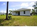 Home's back exterior showcasing a covered patio and grassy yard at 2163 Blaser St, Punta Gorda, FL 33980