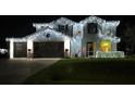 Two-story home with festive lights, showcasing a large garage and well-manicured lawn at 23141 Blackwell Ave, Port Charlotte, FL 33952