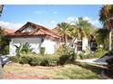Home exterior showcases a red-tiled roof, palm trees, lush landscaping, and a clean white exterior at 956 Harbor Town Dr, Venice, FL 34292
