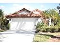 Charming home featuring a red tile roof, white exterior, well-maintained yard, and a two-car garage at 956 Harbor Town Dr, Venice, FL 34292
