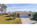 Single-story home with light peach walls, white garage door, and palm trees at 243 Fairway Rd, Rotonda West, FL 33947