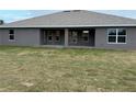 House's back elevation showcasing a covered patio and grassy backyard at 10225 Winnipeg St, Port Charlotte, FL 33981