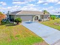 Single-story house with a light-grey driveway and lush green landscaping at 138 Peckham Sw St, Port Charlotte, FL 33952