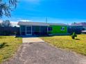 Single-story home showcasing vibrant green paint, a screened-in porch, and a long driveway at 30431 Holly Rd, Punta Gorda, FL 33982