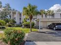 Inviting condo exterior with carport, lush landscaping, and a neatly maintained lawn under a sunny, clear sky at 437 Cerromar Ln # 312, Venice, FL 34293