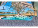 Screened-in pool with brick pavers, complemented by a serene view of the lake and its peaceful surroundings at 2321 Sofia Ln, Punta Gorda, FL 33983